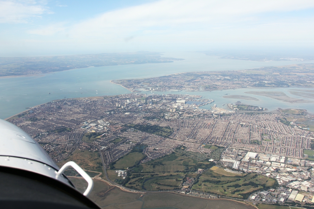 A sensational view on a fantastic clear day - looking west south-west, below us is Langstone Harbour. Portsmouth and its harbour occupy the 
					foreground, with the Solent on the left and the Isle of Wight at upper left, with Cowes visible at the right-hand end of the island. Southampton 
					Water stretches off to the right, and the Solent continues on towards Hurst Castle and Poole Bay in the distance.