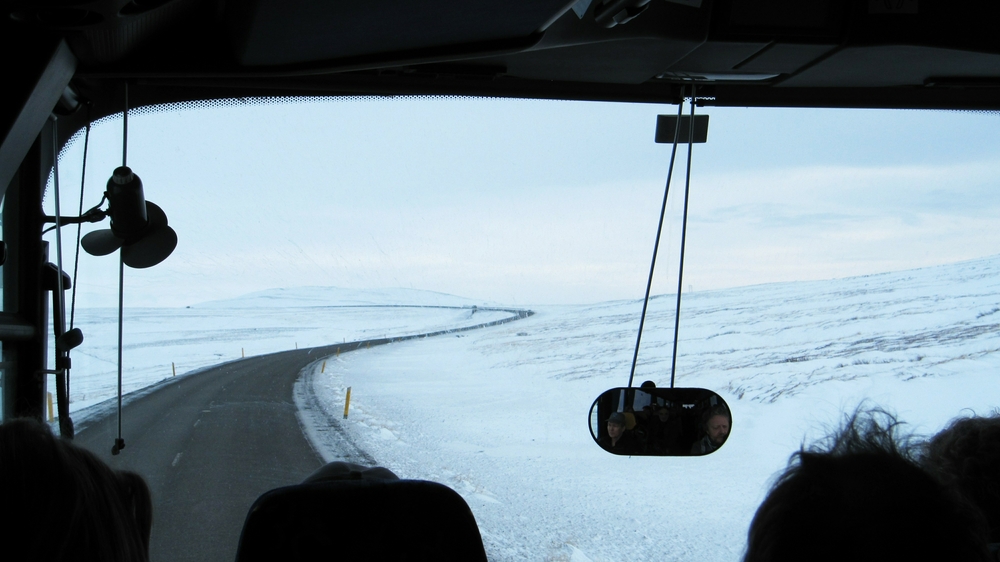 On our way to the national park, looking over the driver's shoulder at the road winding over the desolate, snow-covered landscape.
