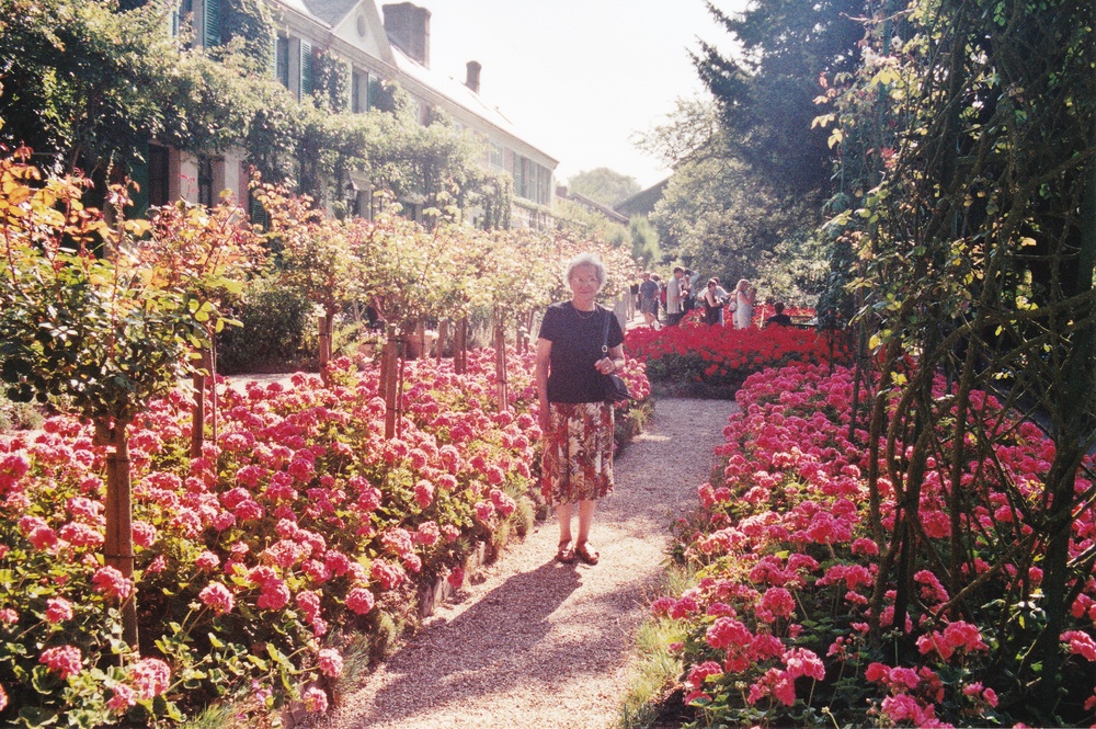 Joyce among beautiful flowers in Monet's Garden - his house at the left.
