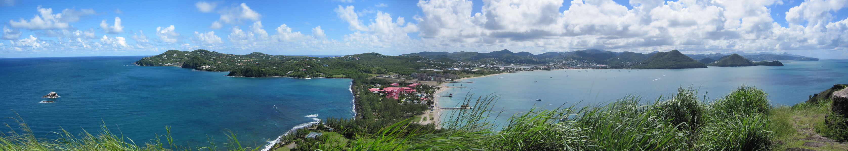 Panoramic view from the top of Signal Peak, from left to right: Cap Estate with the Atlantic beyond, Sandals Grande St Lucian on the
        causeway with the red roofs, Rodney Bay and the view down the west coast of St Lucia. Use the scroll bar to see a panoramic 180 degree view. (745k)